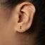 A close-up view of a person's ear with a small gold earring in the earlobe.