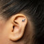 A small silver elephant earring is visible in the person's ear.