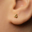 A close-up of a person's ear with a small gold earring featuring the number 4.