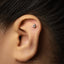 A close-up of a person's ear with a small silver earring in the earlobe.