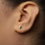 A close-up of a person's ear with a small, colorful earring in the earlobe.