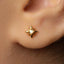 A close-up view of a person's ear adorned with a small gold star-shaped earring.