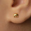 A close-up of a person's ear with a small gold earring featuring a small elephant design.