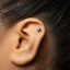 A close-up of a person's ear with a small silver earring in the earlobe.