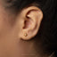 A close-up of a person's ear with a small gold earring featuring a star-shaped gemstone.