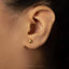 A close-up view of a person's ear with a small gold earring in the earlobe.