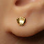 A close-up of a person's ear with a small gold earring featuring a shell design.