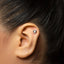 A close-up of a person's ear with a small silver earring in the earlobe.