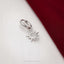 A silver earring with a sun-shaped charm is placed on a red fabric surface.