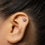 A silver earring with a mushroom design is visible in the person's ear.