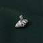 A silver pin with a bird-like design is resting on a dark green fabric.