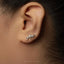 A close-up of a person's ear with a silver earring featuring a leaf design.