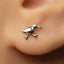 A close-up of a person's ear with a small silver bird earring in the earlobe.