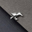A small silver bird figurine is resting on a textured gray surface.