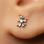 A close-up of a person's ear with a small silver earring featuring a small figure or character attached to it.
