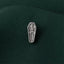 A silver pin with a skeleton design is shown against a dark green fabric background.