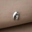 A silver lobster clasp is resting on a beige fabric surface.