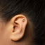 A close-up of a person's ear with a small gold earring in the earlobe.