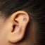 A silver earring with the letter "m" on it is visible in the image.