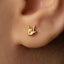 A close-up of a person's ear with a small gold earring featuring a hand sign.