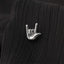 A small silver pin with the hand sign "O" is resting on a black fabric surface.