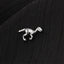 A small silver dinosaur figurine is resting on a black fabric surface.