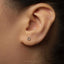 A close-up view of a person's ear with a small silver earring in the earlobe.
