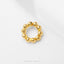 A gold-colored ring with a circular design of small, shiny balls or stones.