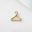 A small gold-colored hanger clip is placed on a white fabric surface.