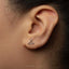 A close-up of a person's ear with a small silver earring in the earlobe.