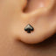 A close-up view of a person's ear with a small black earring featuring a spade symbol in the earlobe.