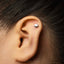 A close-up of a person's ear with a small silver earring in the earlobe.