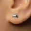 A close-up view of a person's ear with a small silver earring in the earlobe.