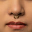 A close-up portrait of a young woman with long, dark hair and a nose piercing.