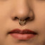 A close-up portrait of a young woman with long, dark hair and a nose piercing.