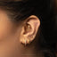 A close-up of a person's ear adorned with multiple gold earrings, including a hoop earring and two smaller earrings with a diamond accent.