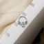 A silver dragon-shaped piercing ring is placed on a white block.