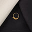 a gold ring with a floral design, placed on a black fabric surface.