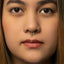A close-up of a woman's face, focusing on her nose and lips, with a gold nose ring and red lips.