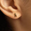A close-up of a person's ear with a small gold-colored earring featuring a bird design.