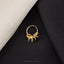 A gold ring with an octopus design is placed on a black fabric background.