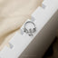 A silver dragon-shaped piercing ring is placed on a white block.