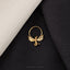 A gold-colored dragon-shaped earring is displayed against a black background, with a white fabric or material on the left side.