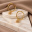 a pair of gold earrings with an octopus charm, displayed on a marble surface.