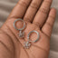A hand holding a pair of silver earrings with octopus designs.