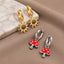 a pair of earrings, one with a sun-shaped charm and the other with a mushroom-shaped charm, both featuring metallic finishes.