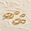 a collection of gold hoop earrings arranged on a textured surface.